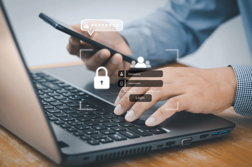 A person logging into a secure system on a laptop while using a smartphone, representing cloud security and multi-factor authentication.